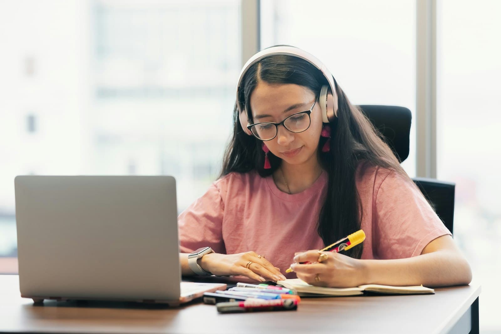 A learner with headphones taking notes during a live online lesson
